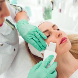 Kosmetikerin führt eine Ultraschall-Gesichtsbehandlung bei einer Kundin durch