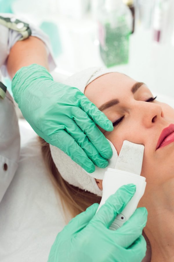 Kosmetikerin führt eine Ultraschall-Gesichtsbehandlung bei einer Kundin durch