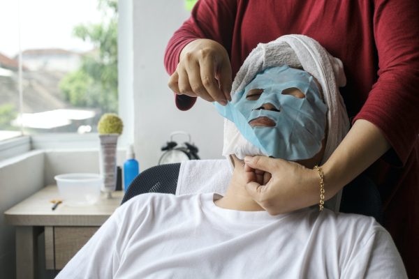 Person bei einer pflegenden Gesichtsbehandlung mit Tuchmaske